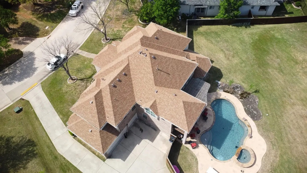 Aerial view of a completed tan shingle roof installed by E Torres Solutions