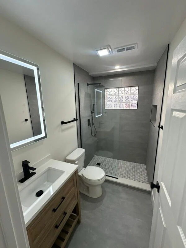 Bathroom example with illuminated mirror and shower enclosure.