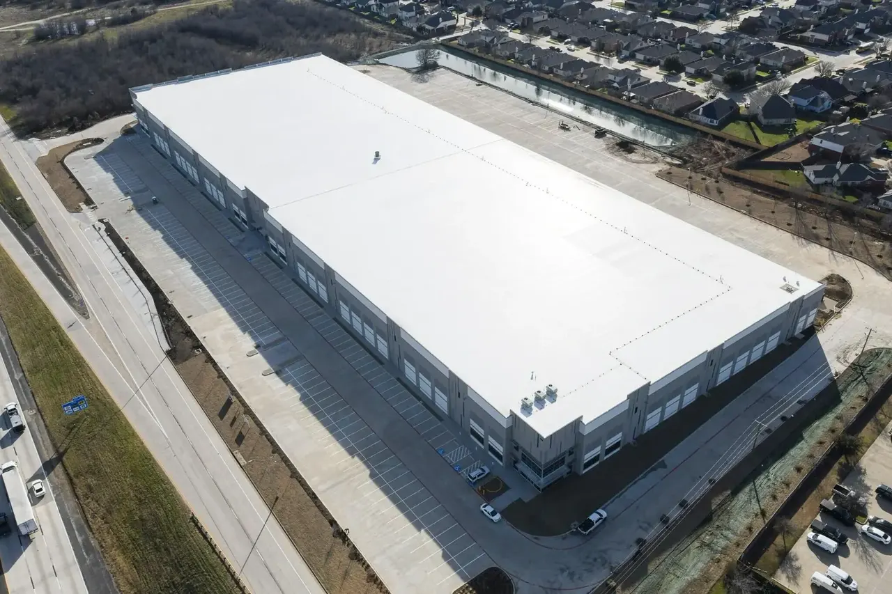 Aerial view of a large commercial building with a white low-slope membrane roof
